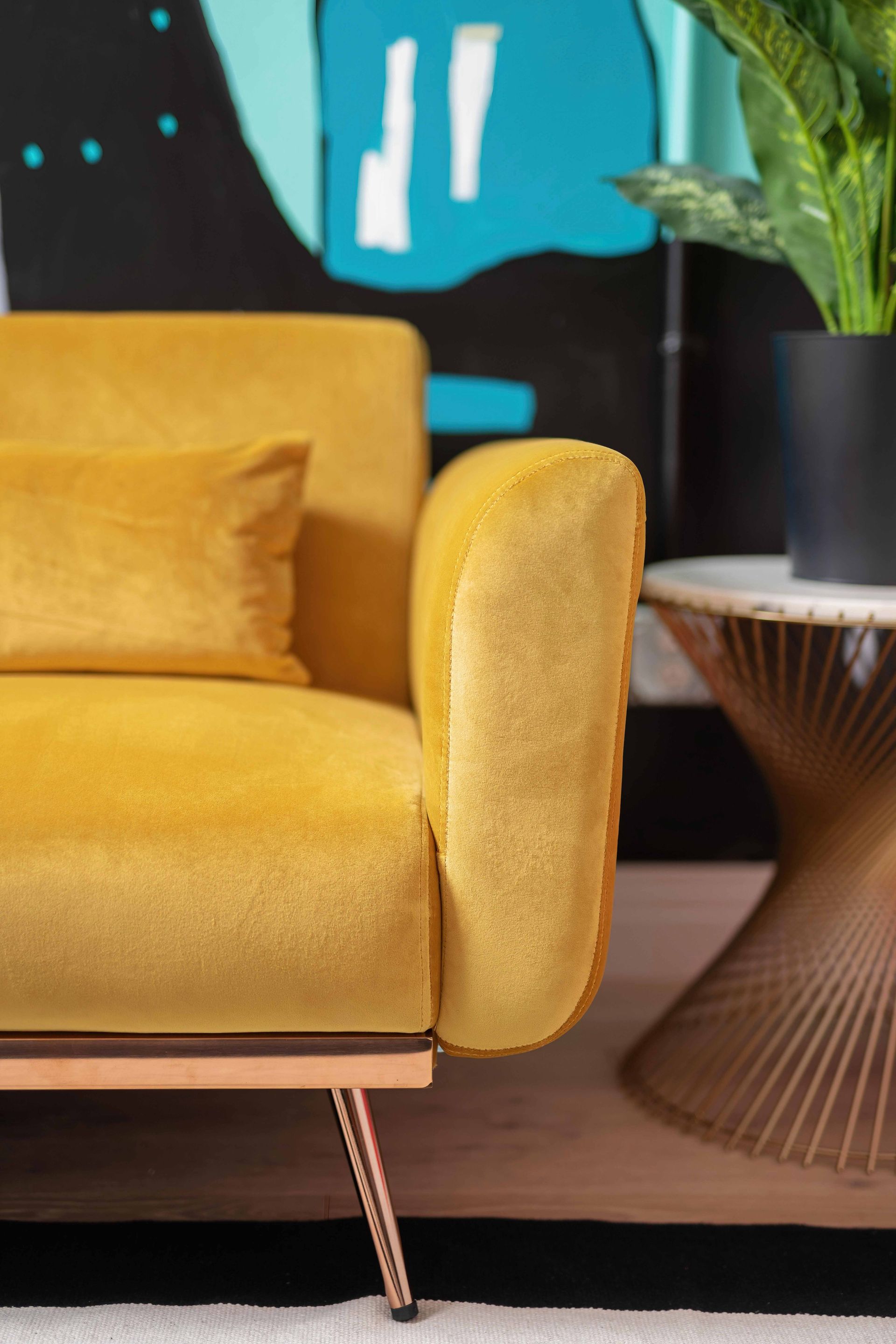 Yellow sofa beside a round side table and plant in a modern living room