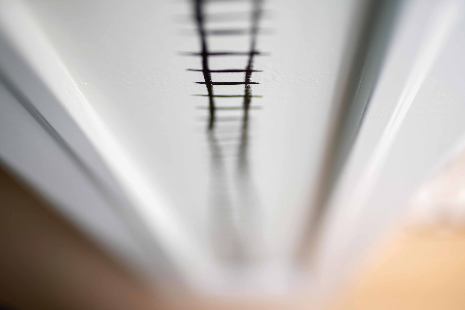 Blurred view down a white hallway with a dark ceiling ladder or track running overhead