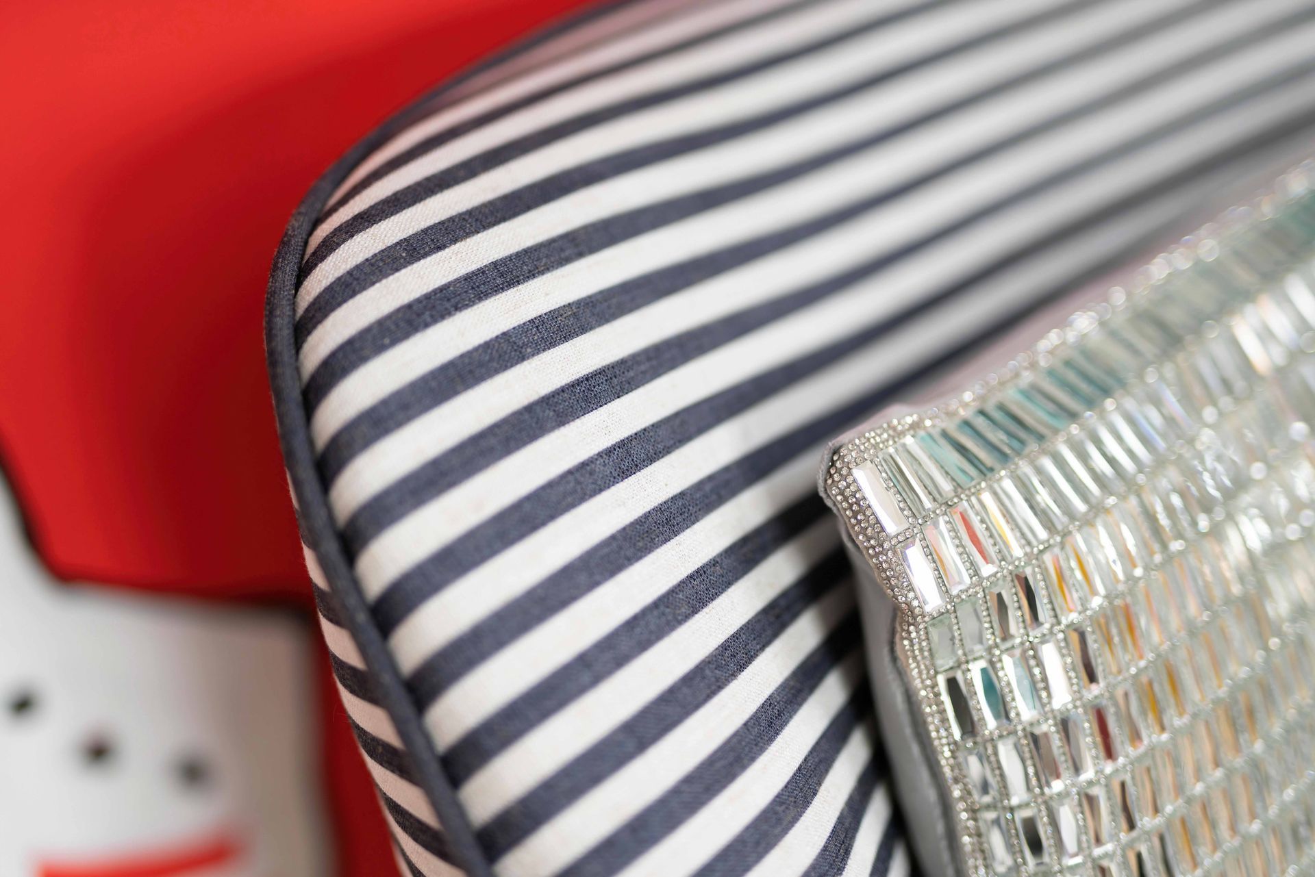 Striped cushion beside a red chair and a metallic woven pillow close-up