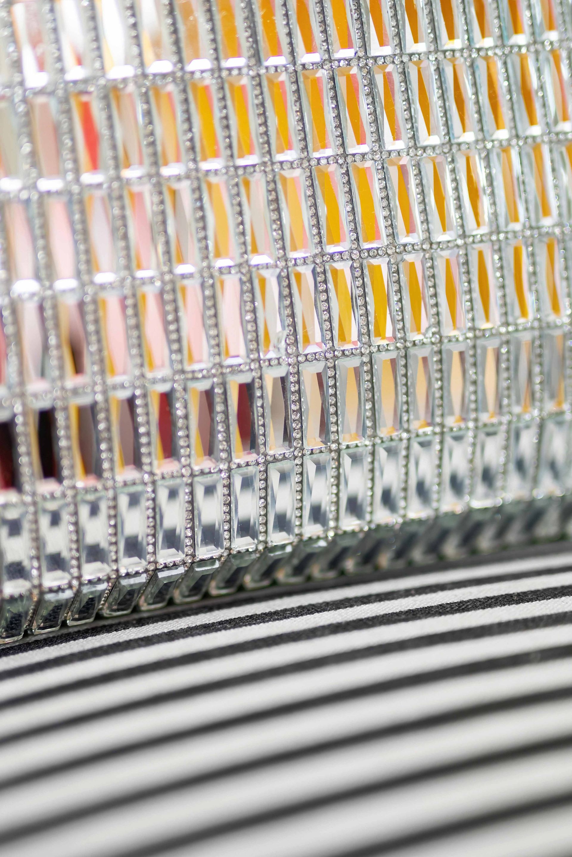 Close-up of a colorful patterned metal fence with black-and-white striped pavement below