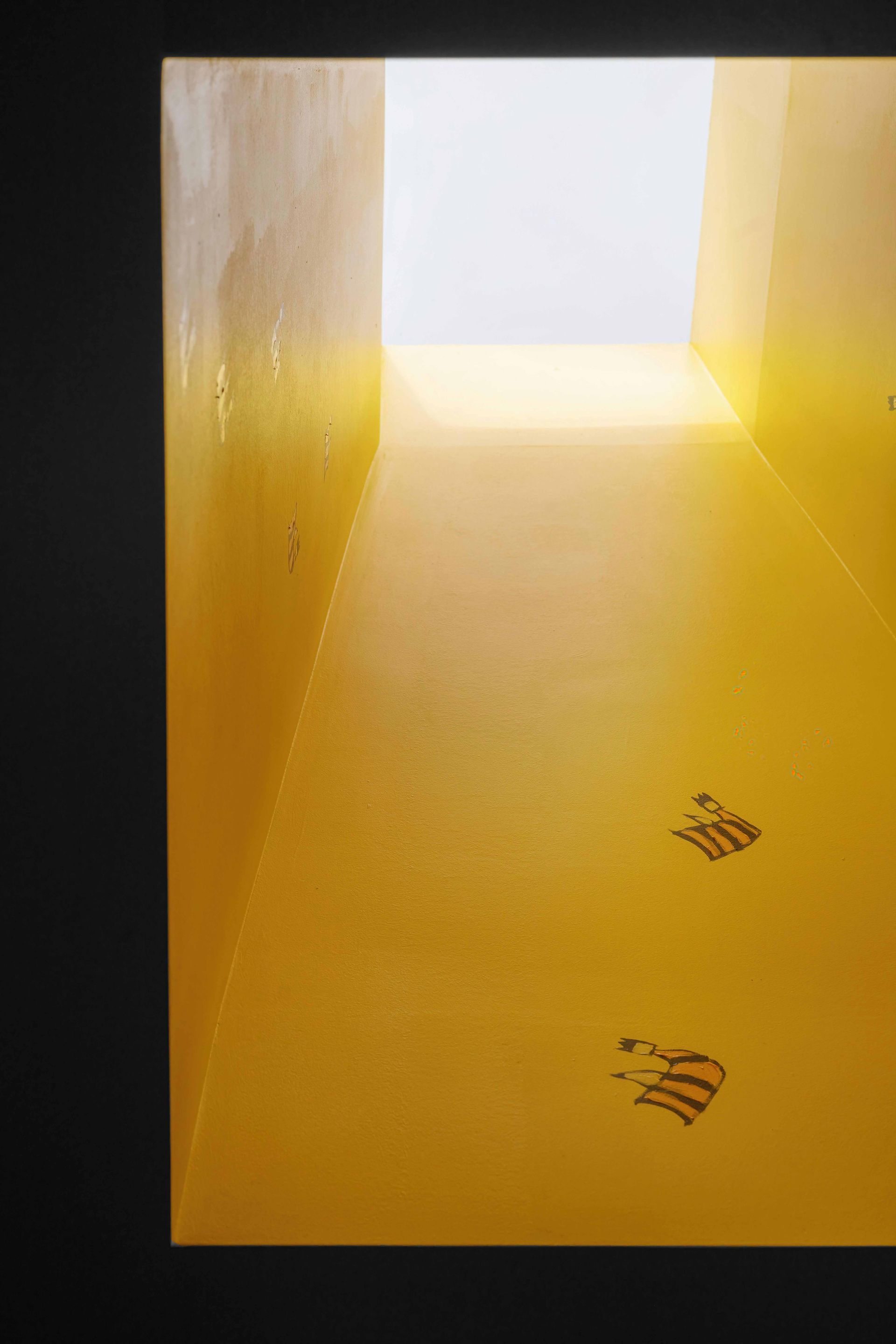 Yellow tunnel or corridor with bright light at the end and small footprints on the floor.