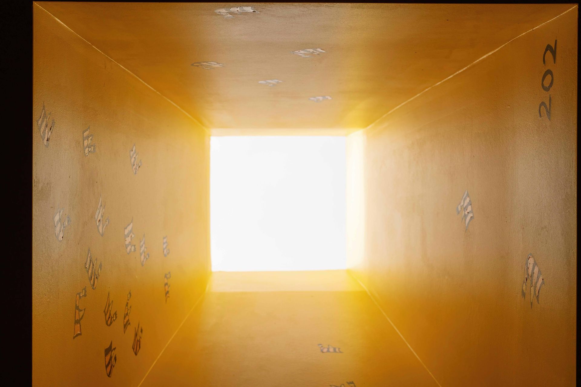 Inside a yellow cardboard box, looking up toward a bright square opening