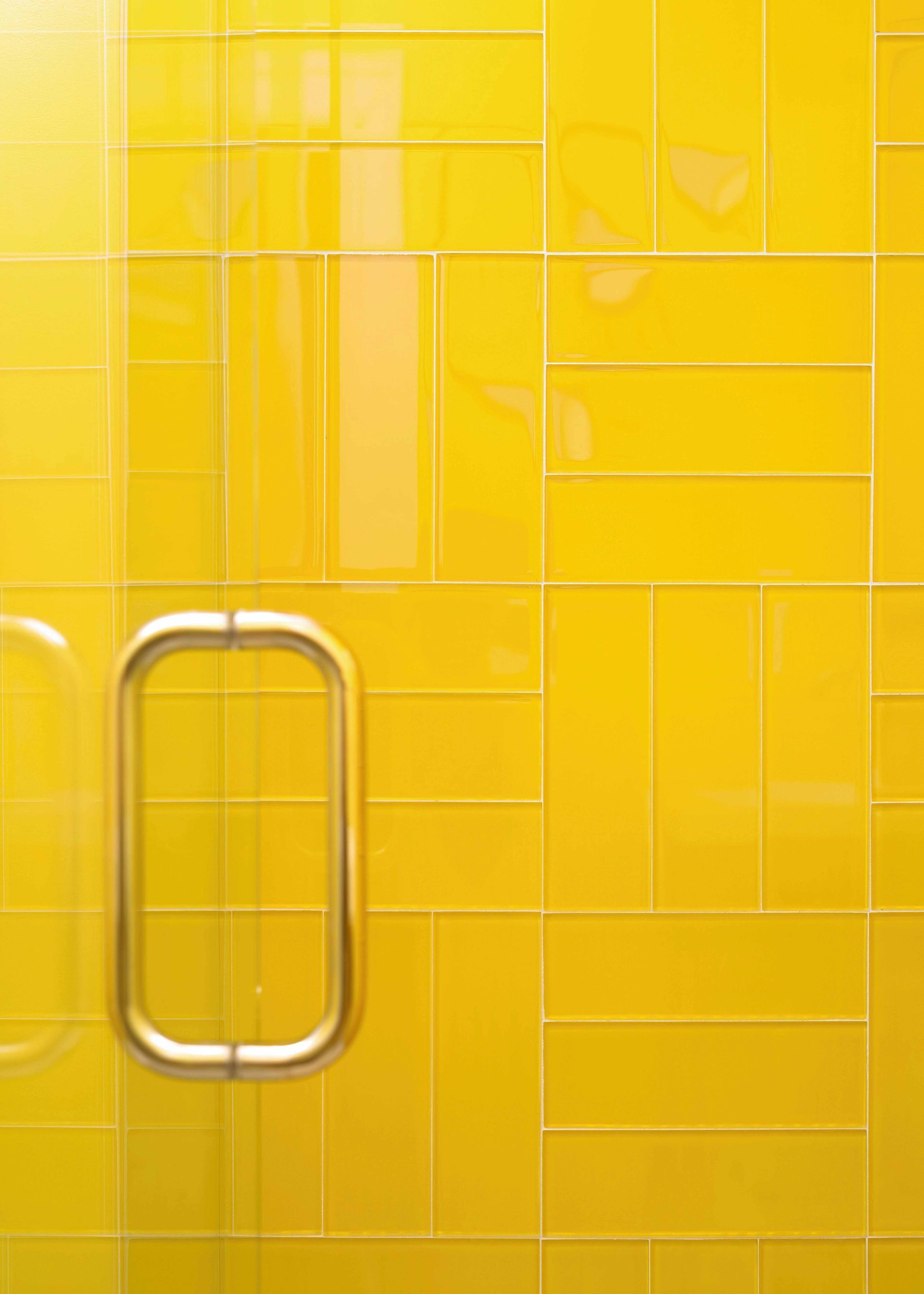 Yellow tiled shower door with a metal handle