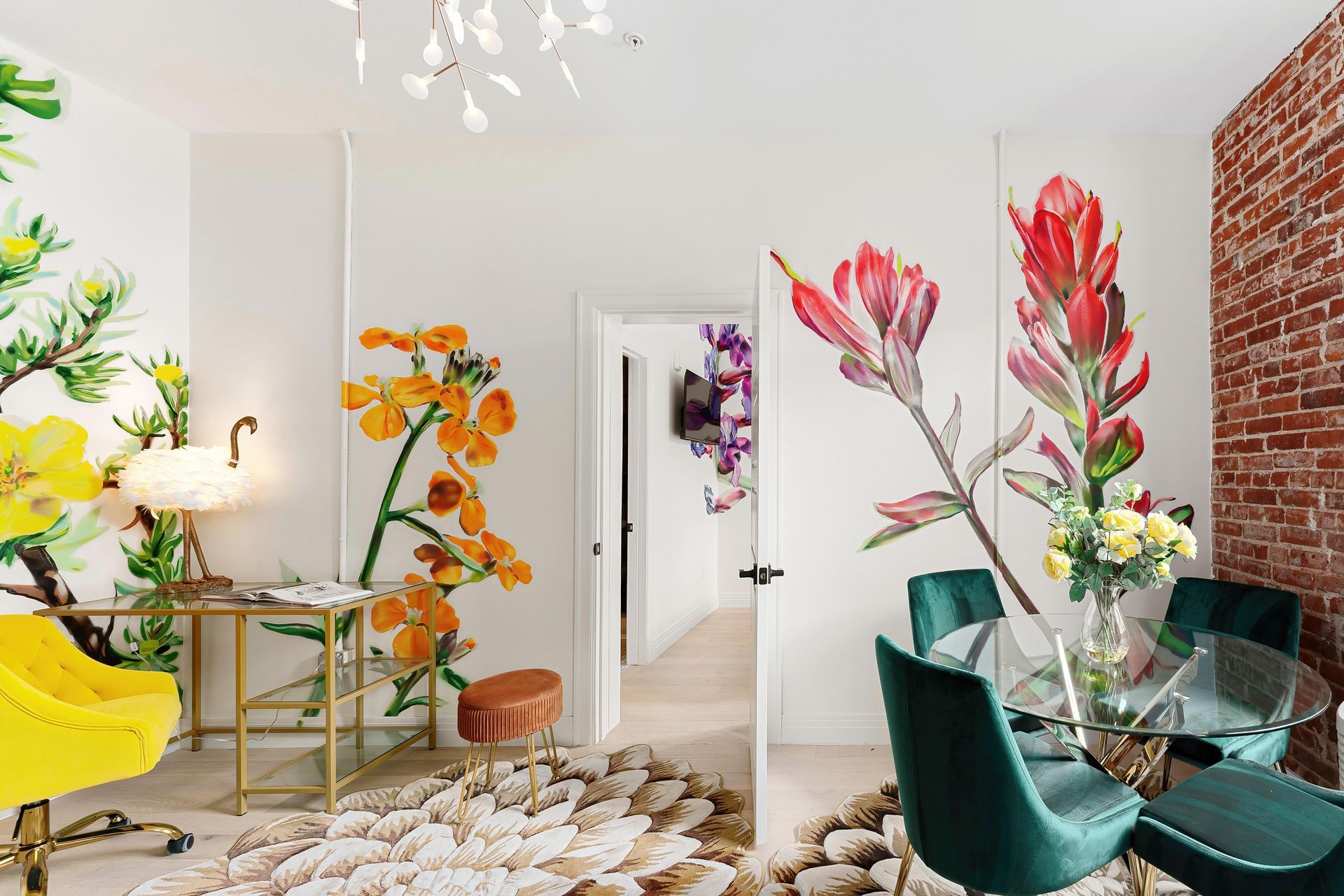Bright modern dining room with floral wall art, green chairs, a yellow accent chair, and brick accent wall.