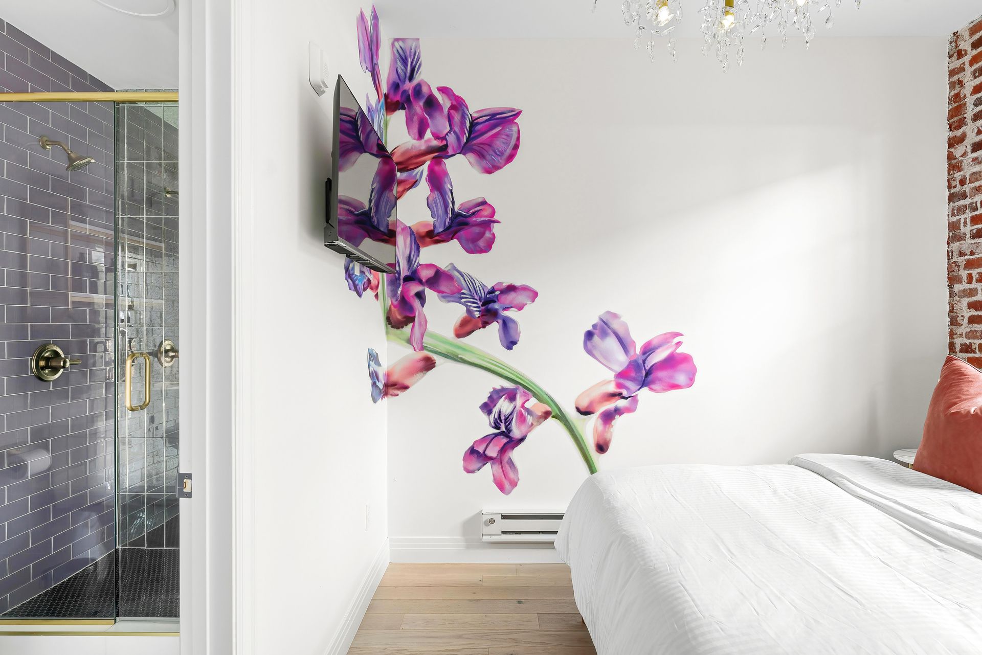 Bright bedroom with pink-purple floral wall art above a bed and a glass shower on the left.