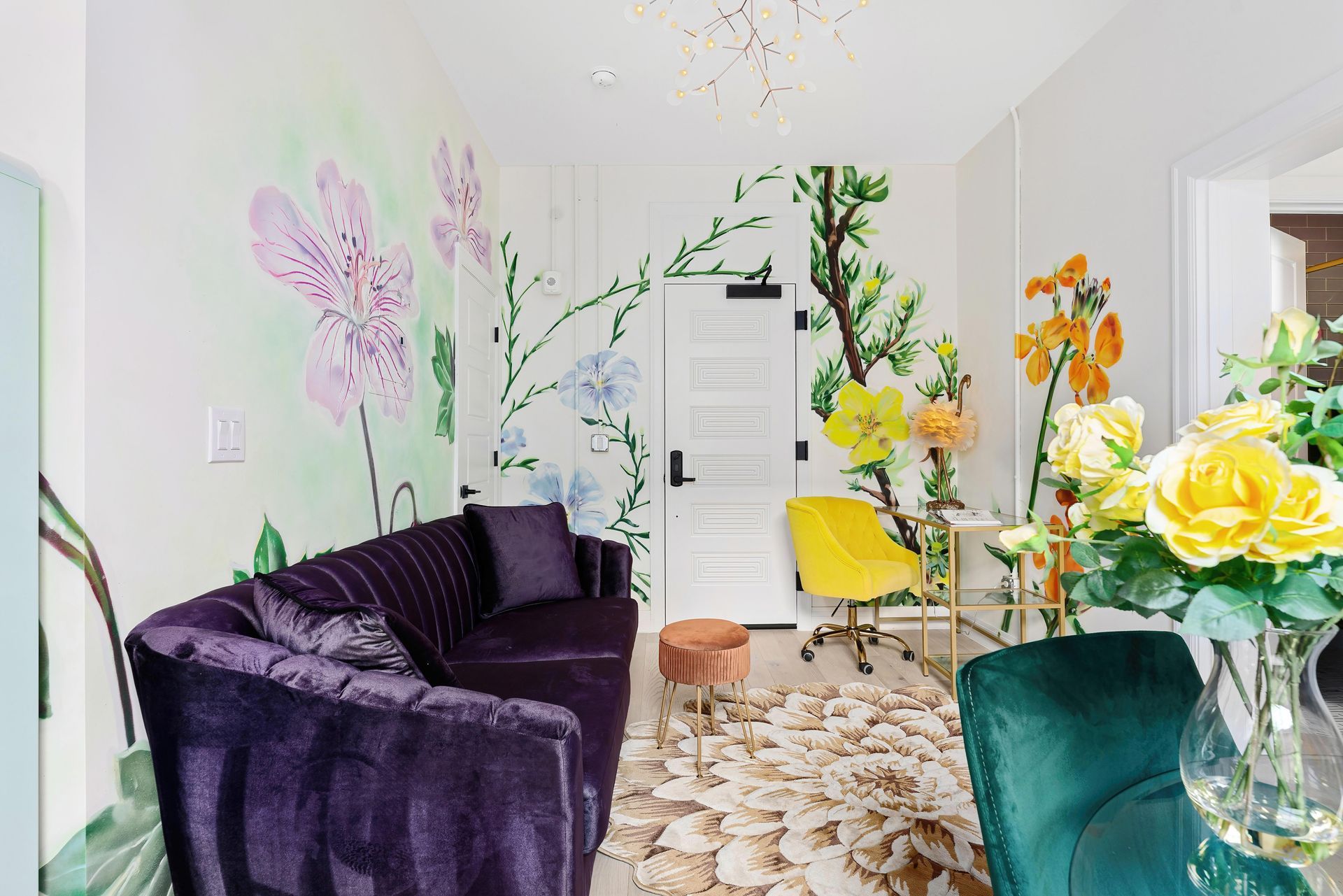 Bright living room with purple sofa, floral wall art, and colorful flowers on a glass table