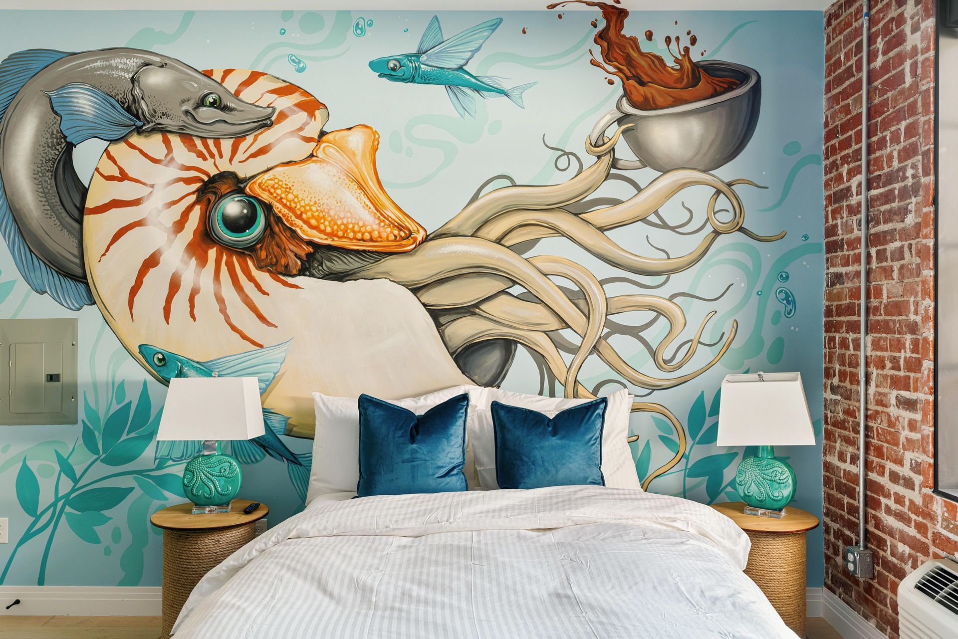 Colorful bedroom mural of a giant octopus, seagulls, and boats above a bed with teal pillows