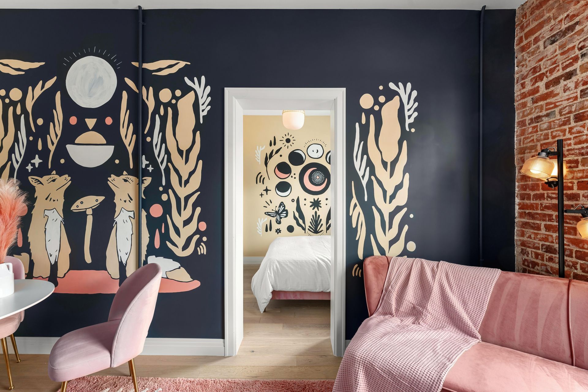 Stylish living room with dark mural walls, pink sofa, and doorway to a bright bedroom