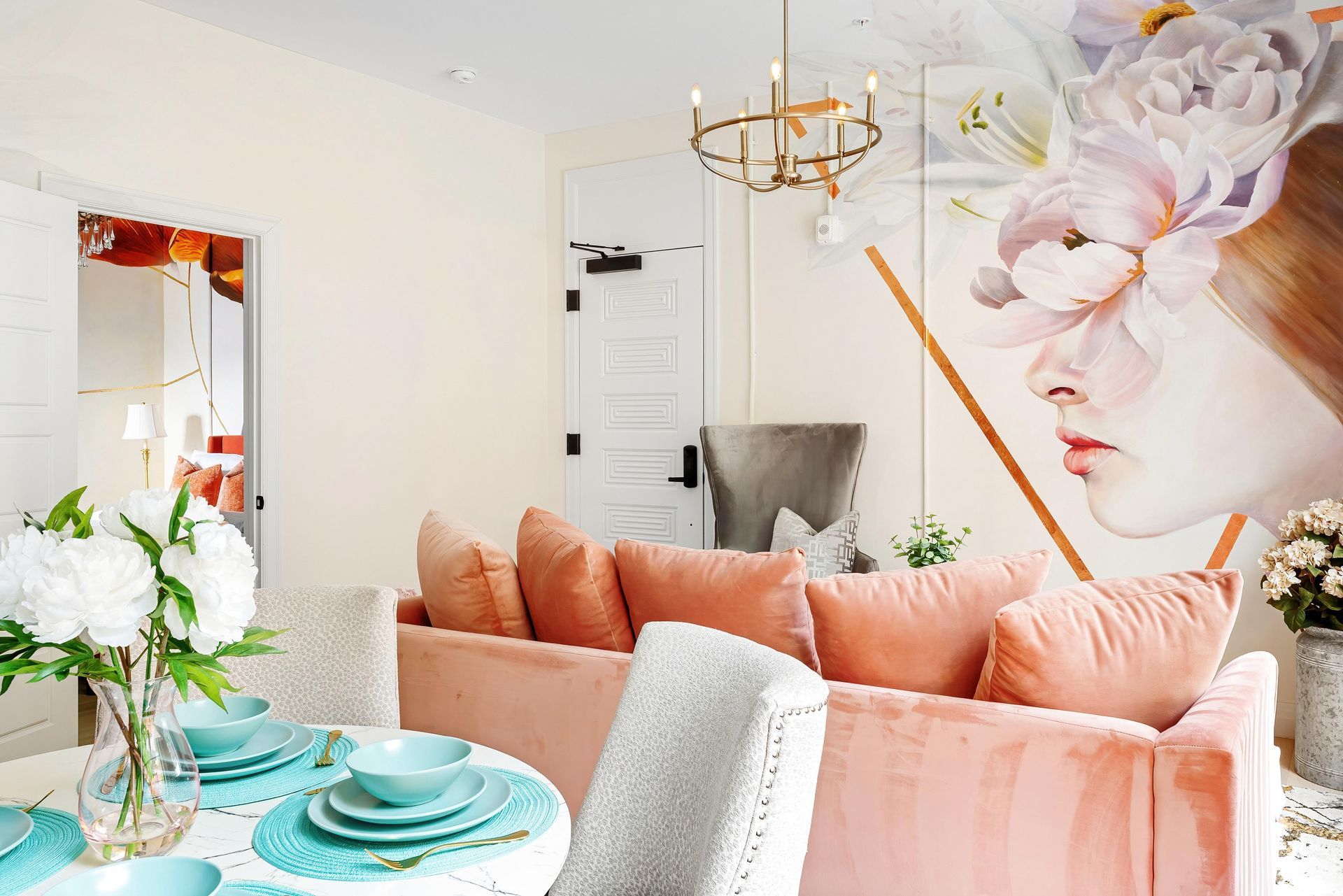 Bright pastel living room with pink sofa, floral wall art, and teal dining table settings