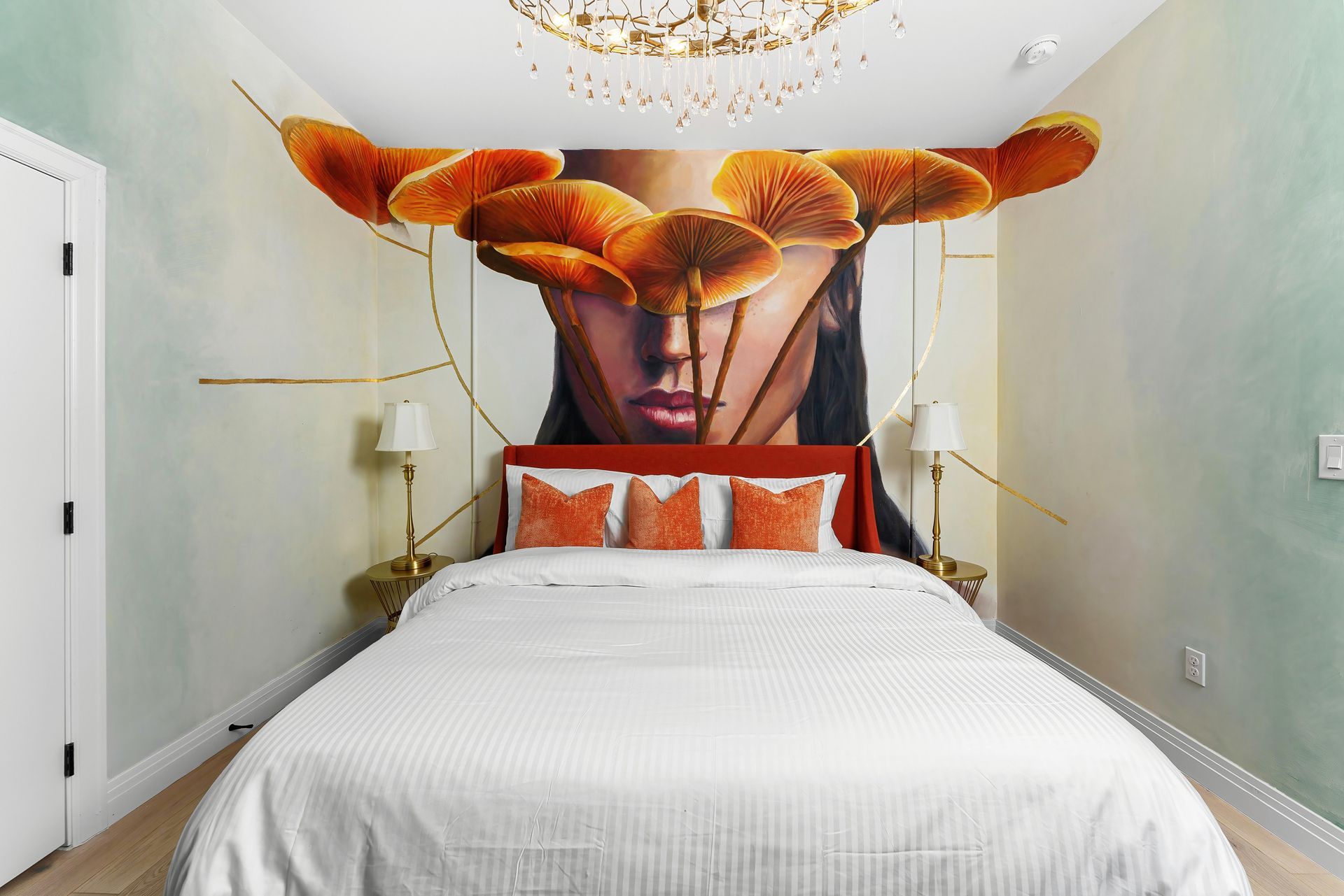 Bedroom with large mural headboard, white bed, and orange cushions under a decorative ceiling light
