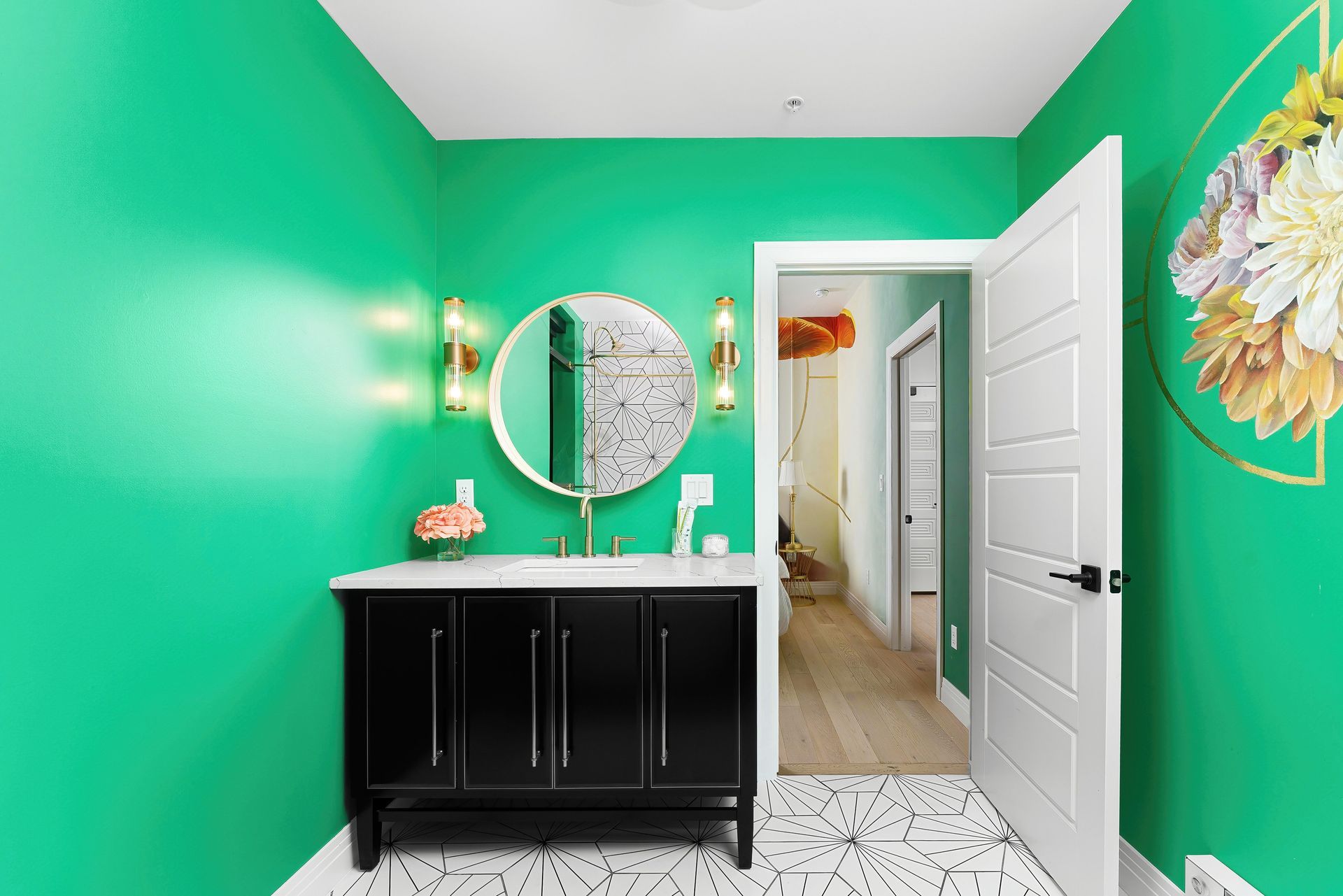 Bright green bathroom with black vanity, round mirror, white tiled floor, and open door to hallway