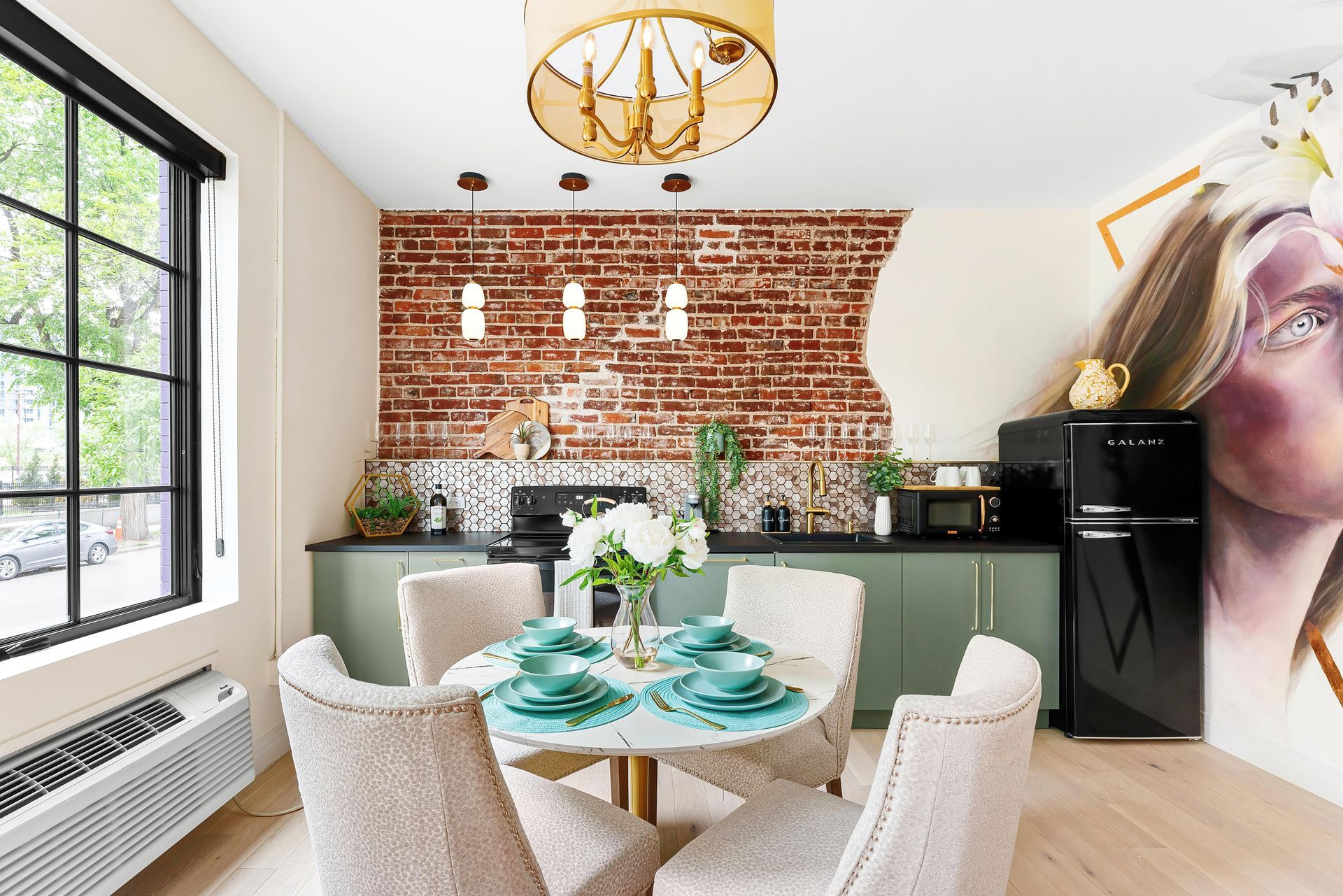 Bright dining area with brick accent wall, round table, and modern kitchen seating by large window