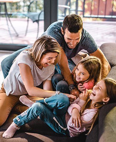 Family tickling and laughing on a couch.
