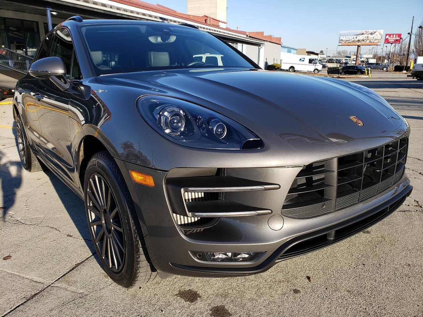 A gray porsche macan turbo is parked in a parking lot.