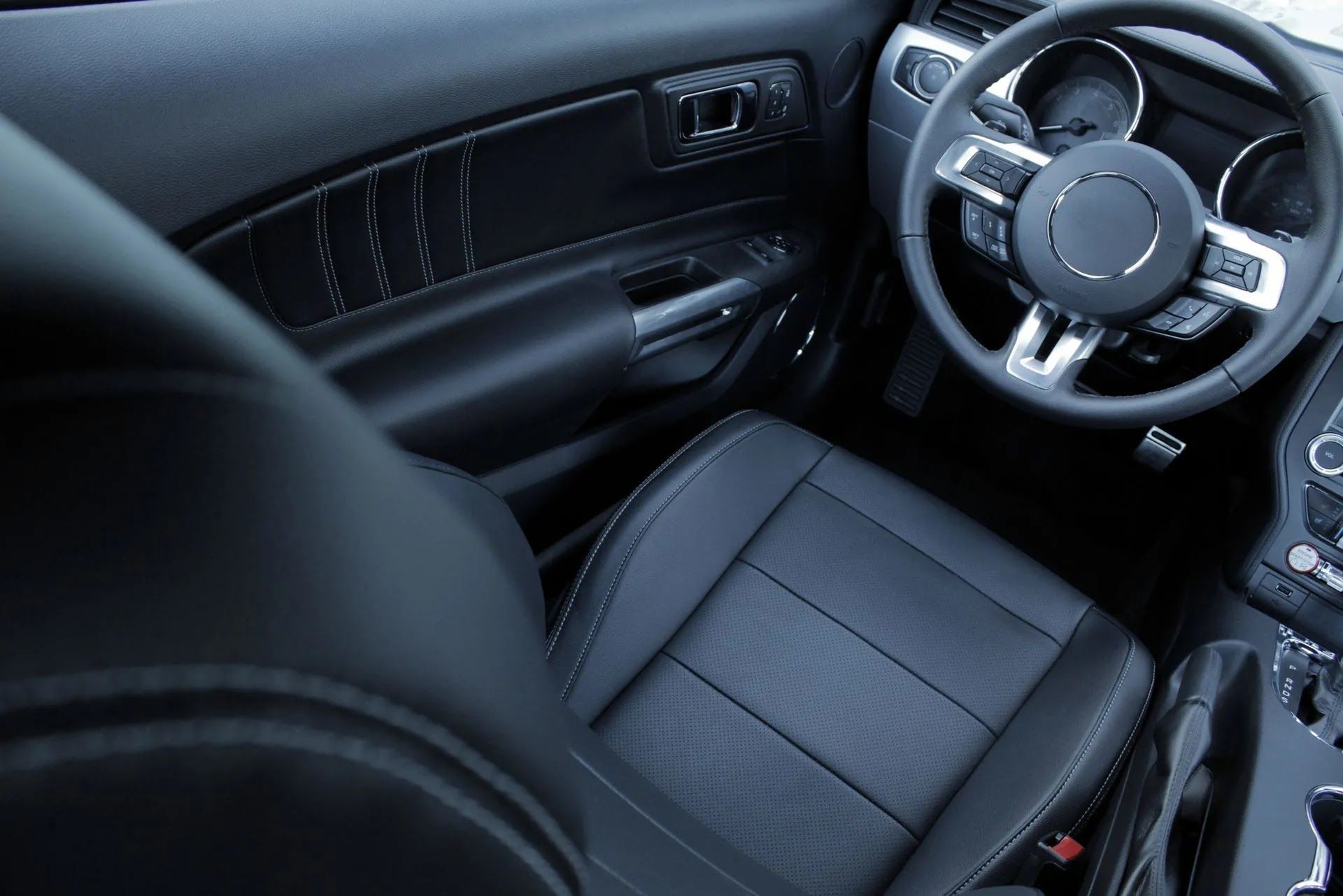 Black leather interior of a car, including the steering wheel and driver's seat.