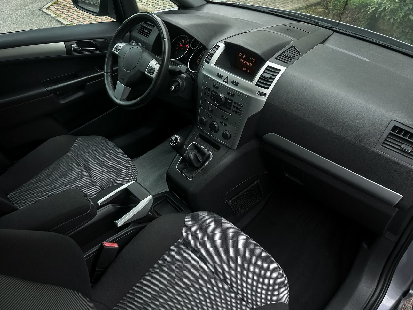 Car interior with black seats, steering wheel, and center console in a gray dashboard cabin