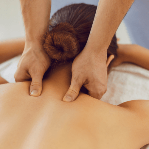 Hands giving a back massage to a person lying face down on a towel
