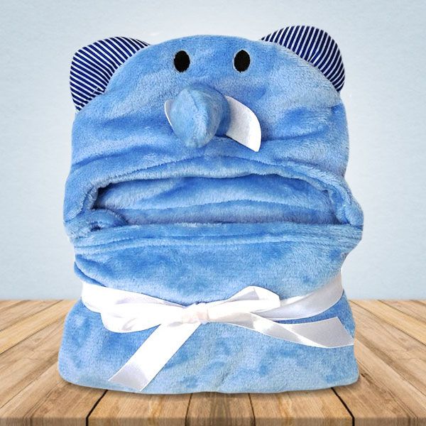 Op een houten tafel ligt een blauw babydekentje met een olifantenkapje.