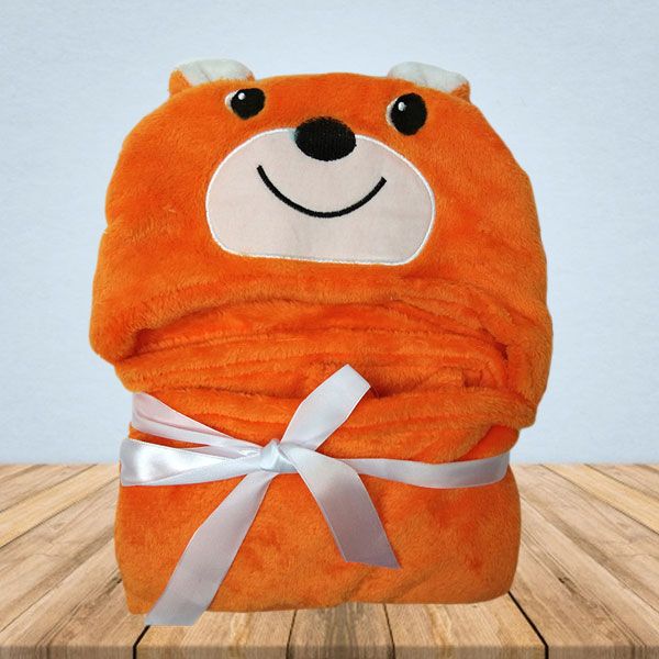 Een oranje deken met een teddybeergezicht erop