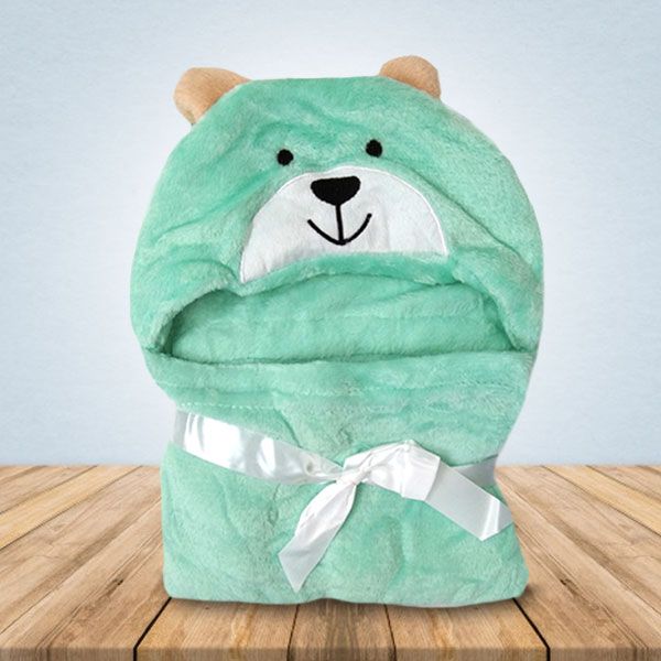 Een groene teddybeerdeken ligt op een houten tafel.