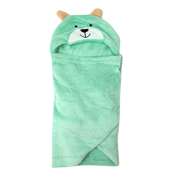 Een groene teddybeerdeken ligt op een houten tafel.