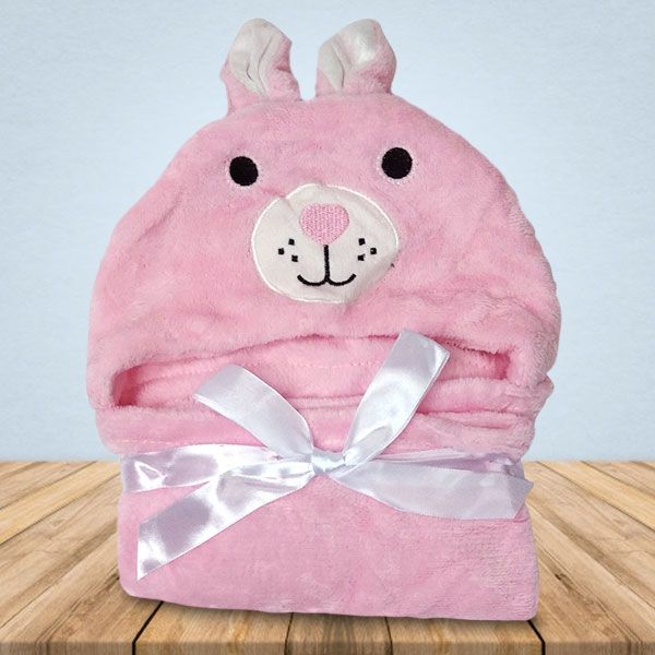 Op een houten tafel ligt een roze deken met een konijnengezichtje erop.