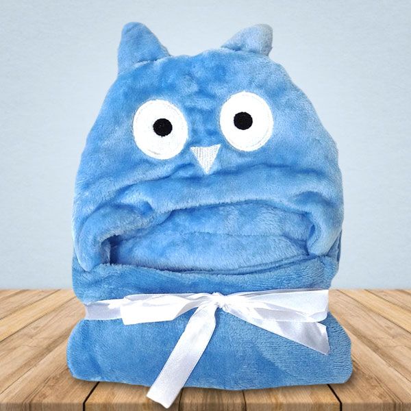 Een blauwe deken met een uil erop ligt op een houten tafel