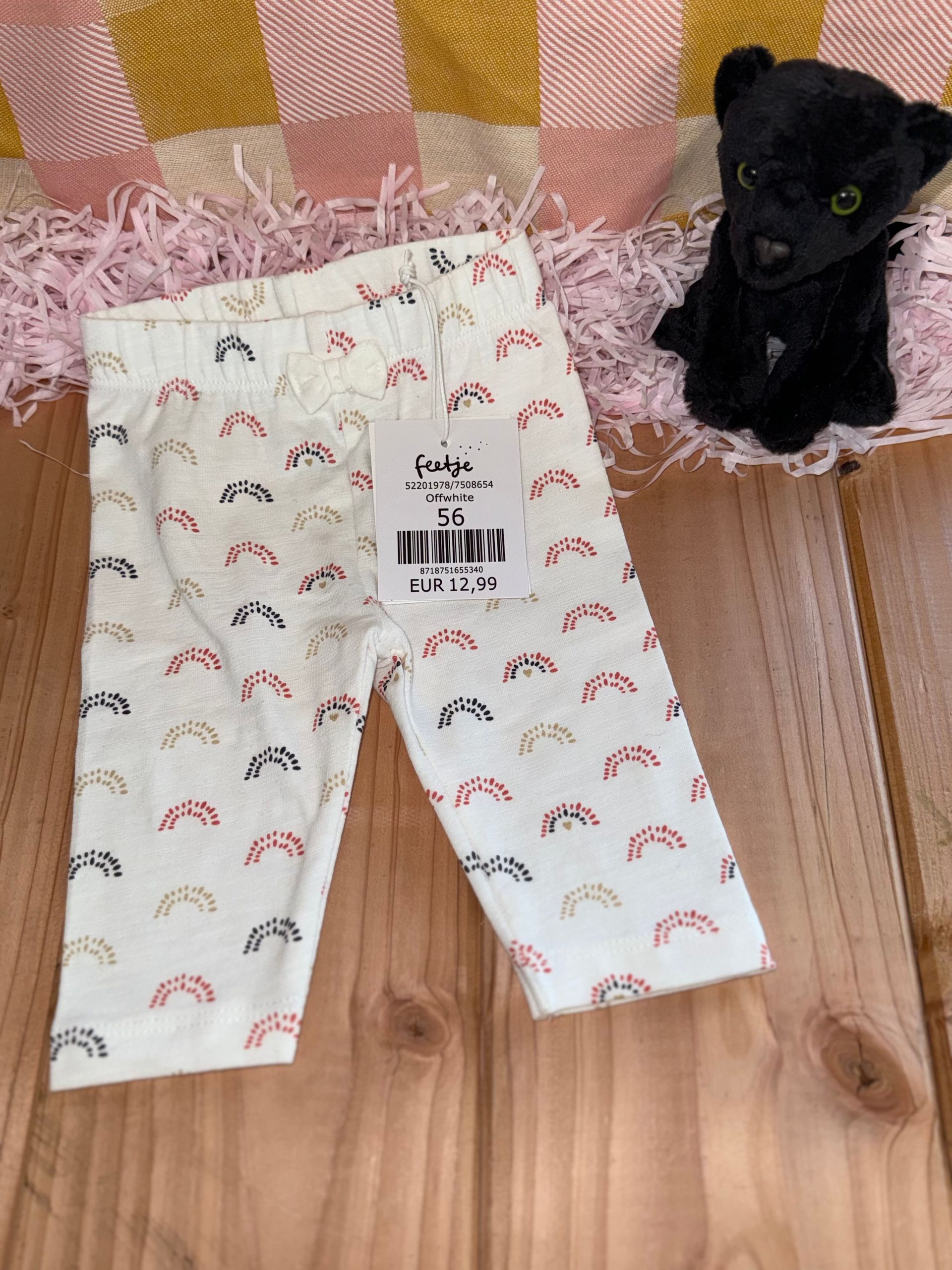 Een zwarte panter zit naast een broek op een houten tafel.