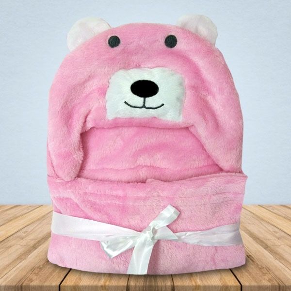 Een roze teddybeerdeken ligt op een houten tafel.