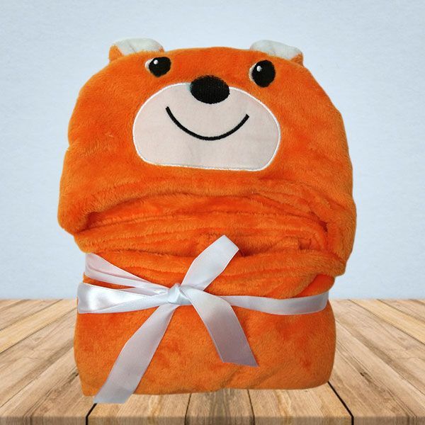 Een oranje deken met een teddybeergezicht erop