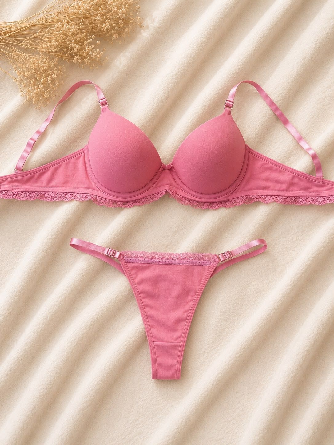 Conjunto de lencería de sujetador y tanga de encaje blanco sobre un fondo de tela texturizada beige.