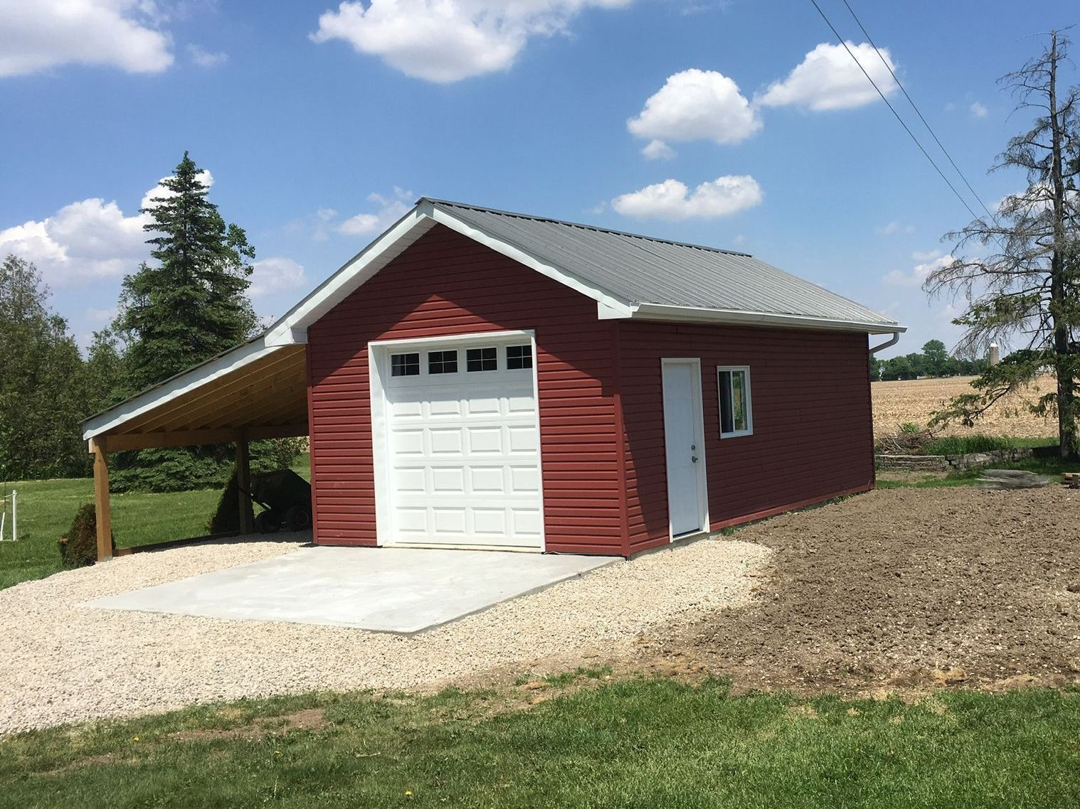 A red garage with a white door and a carport built by Ironside Construction