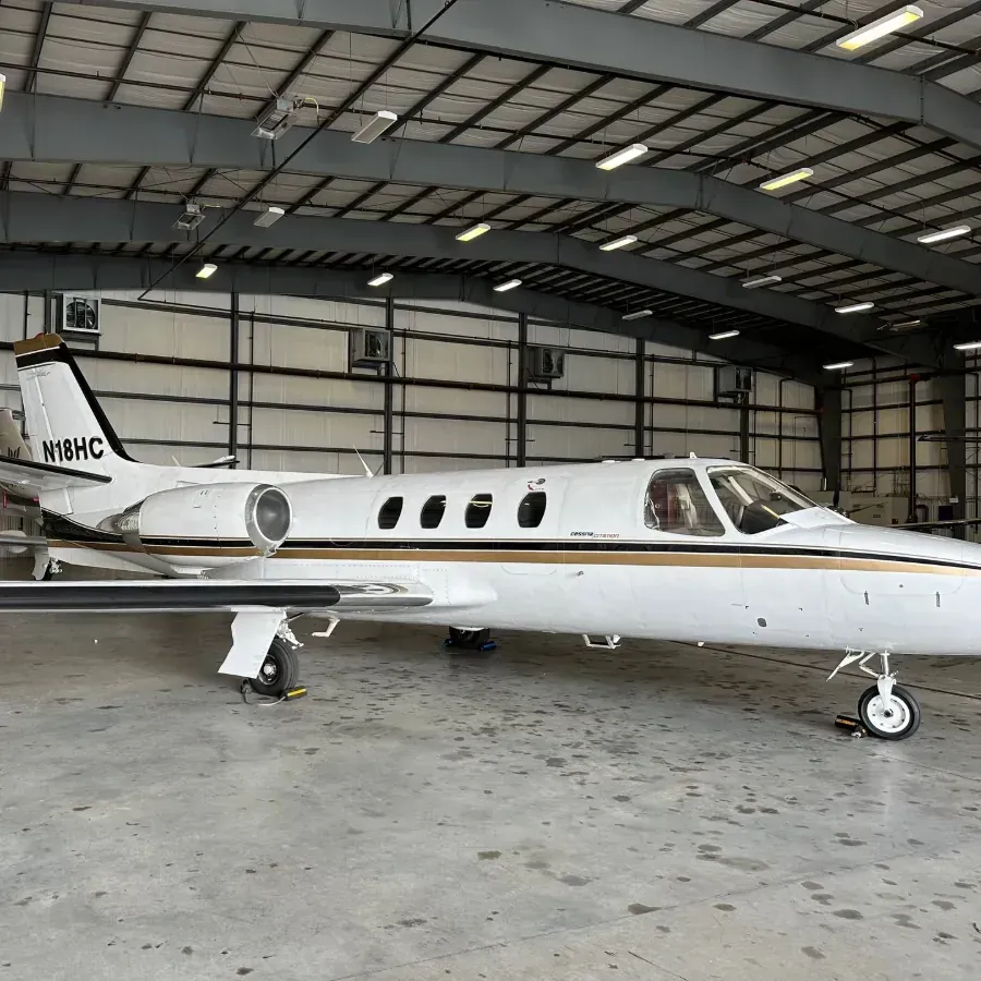 Small white private jet parked inside a hangar
