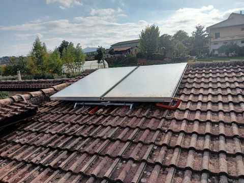 Pannelli solari installati su un tetto di tegole rosse sotto un cielo parzialmente nuvoloso.