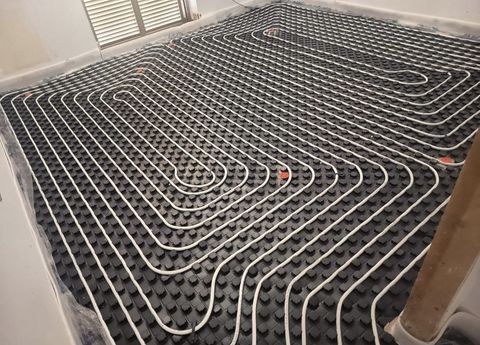 Tubi neri a spirale disposti ad anello sul pavimento, probabilmente per l'installazione di un impianto di riscaldamento a pavimento.