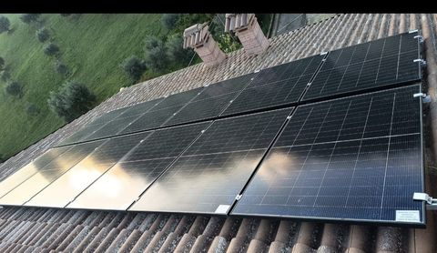 Pannelli solari installati su un tetto inclinato accanto a campi verdi.