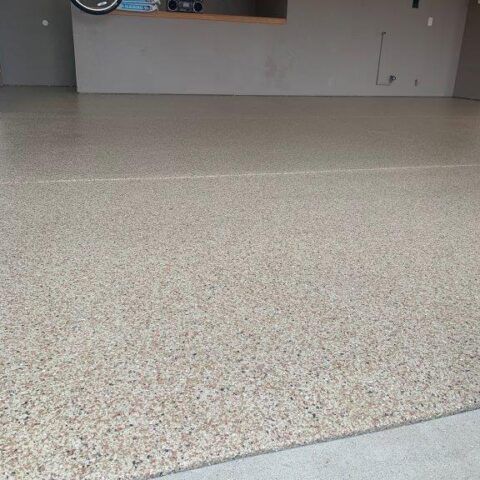 Empty speckled floor in a mostly bare indoor room with a wall and counter in the background