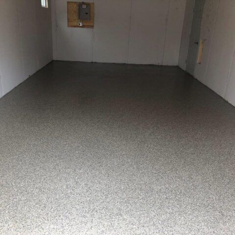 Empty gray-floored room with white walls and a small wall opening on the far side