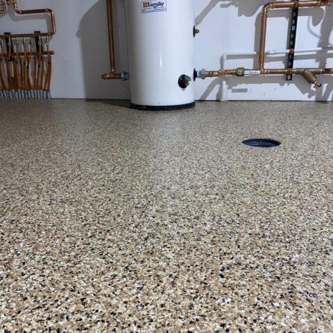 Speckled epoxy floor in a utility room with pipes and a white water heater