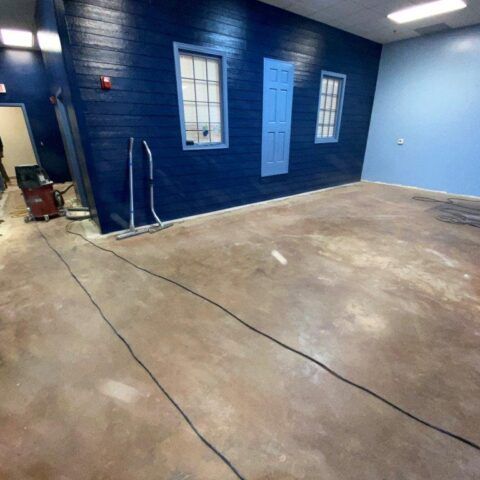 Empty garage-like room with blue walls, concrete floor, and windows and doors painted blue