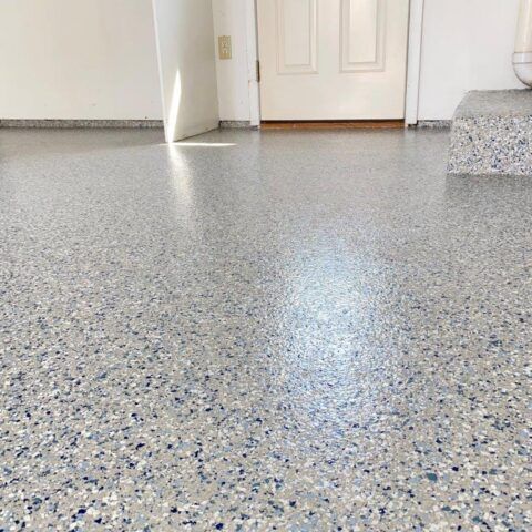 Speckled gray epoxy floor in a bright room with a white door in the background