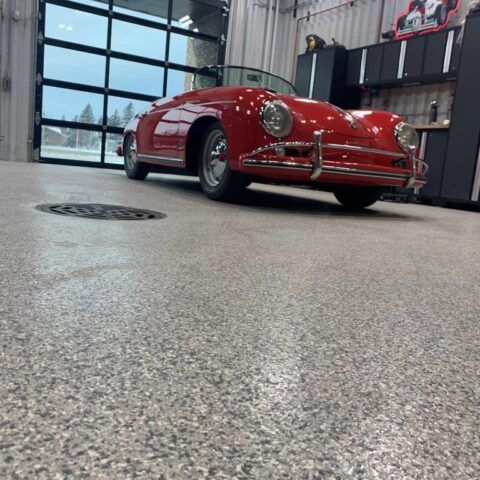 Red vintage sports car parked in a garage, shot from a low angle.