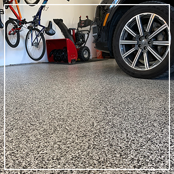 Garage floor with a bicycle, red mower, and car tire in view