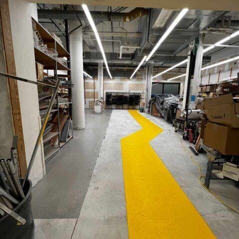 Industrial warehouse aisle with a bright yellow zigzag floor path and shelving on both sides
