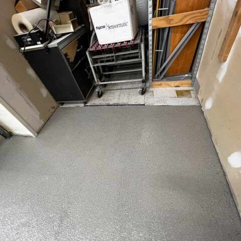 A gray-carpeted entryway with carts, a cabinet, and a narrow doorway cluttered with stored items.