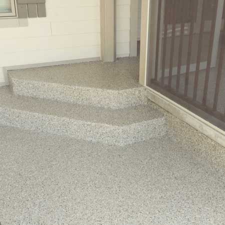 Speckled concrete porch steps beside a metal security door and railing