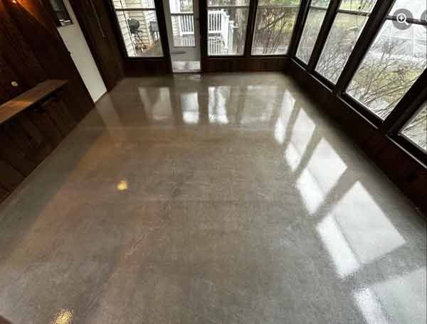 Empty polished indoor room with large windows reflecting light on the floor