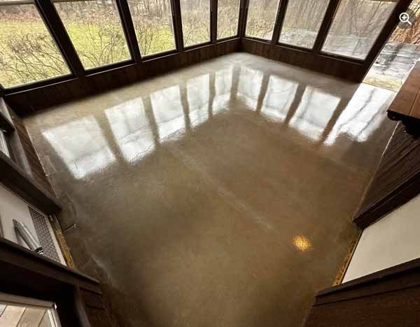 Polished concrete floor reflecting large windows in a sunlit room