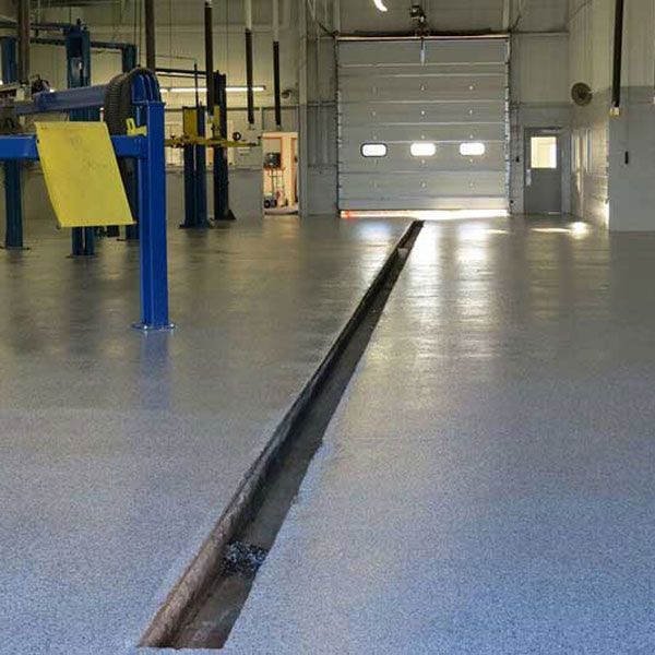 Auto repair shop with a long floor service trench and blue lift posts