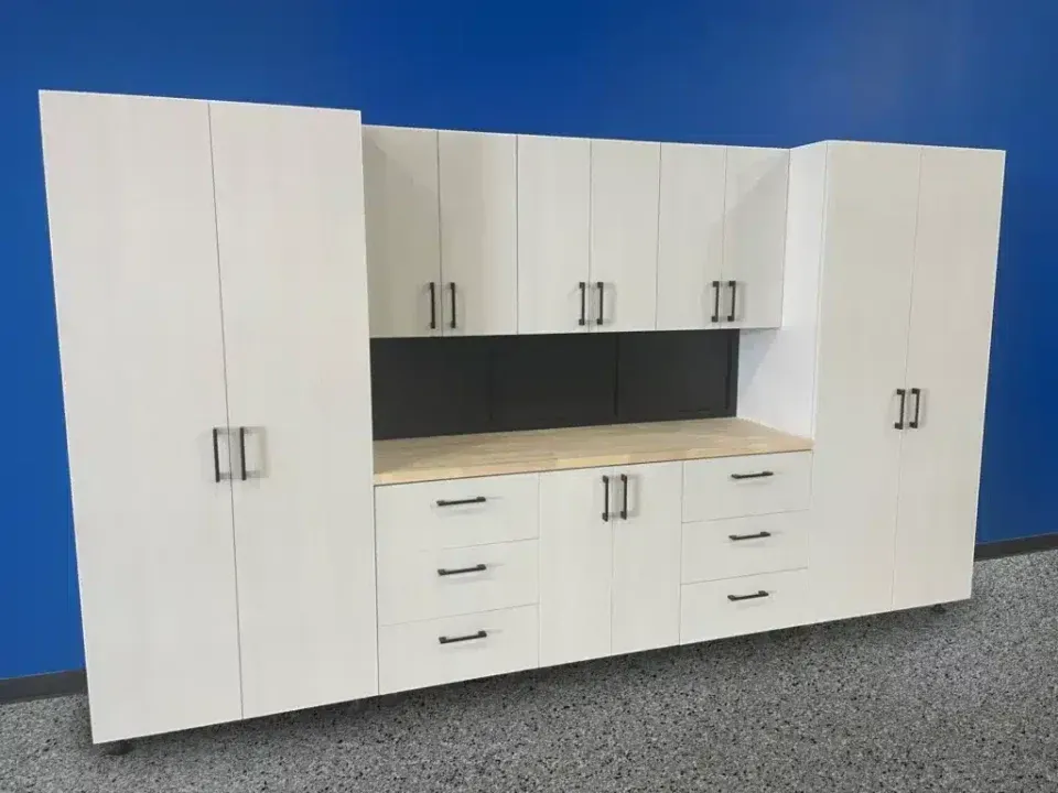 White office cabinetry with drawers and doors against a blue wall and gray carpet.
